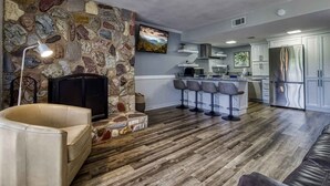A modern kitchen with a stone accent wall, a built-in TV, and a bar area with stools.