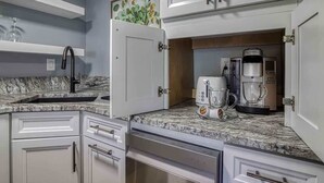 A kitchen with white cabinets, a granite countertop, a coffee maker, and a toaster.