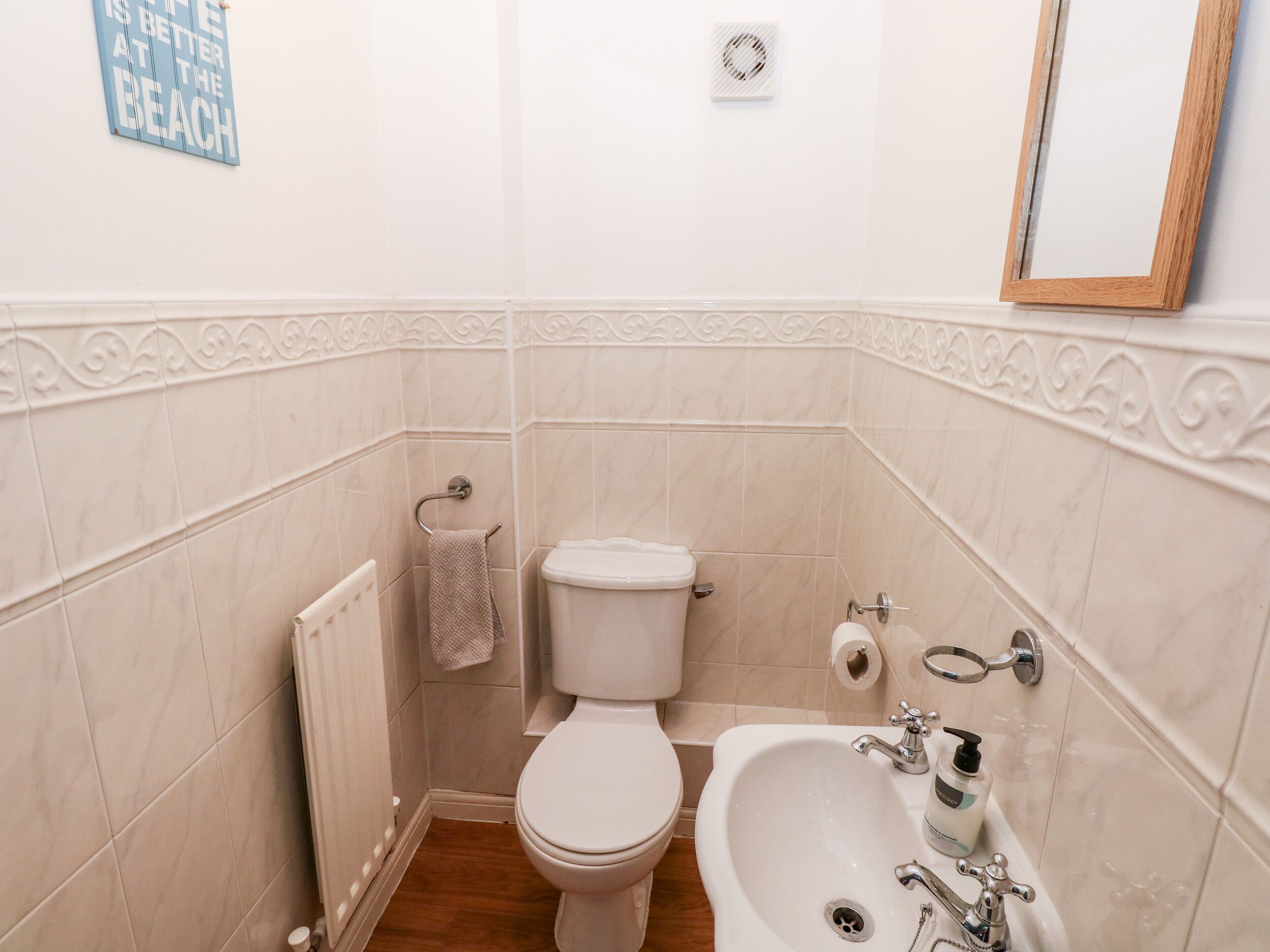 Egy fürdőszoba, amelyben WC, mosdókagyló és törölközőtartó található.