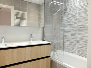 Un bagno moderno con un mobile doppio lavabo, cabina doccia in vetro e un grande specchio.