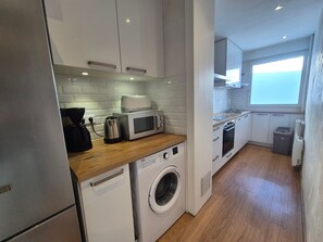 A compact kitchen with a washing machine, a microwave, and a coffee maker. - Renovated apartment, 7 ppl, near slopes, balcony, pets allowed (Tignes)