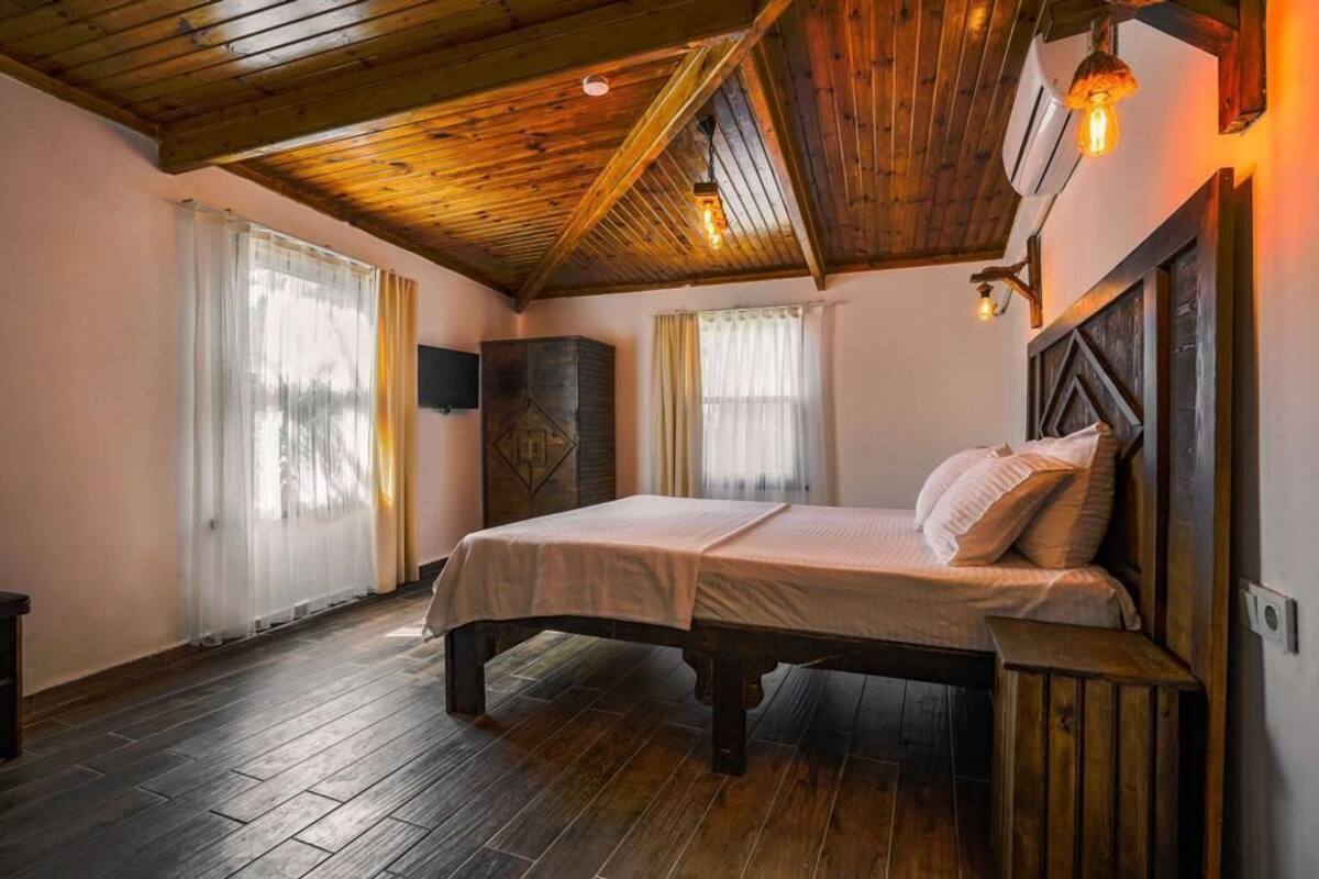 A bedroom with a wooden ceiling, a bed with white linens, and a wooden headboard.