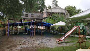 Children can play on the swing set, slide, and climbing structure in this playground area.
