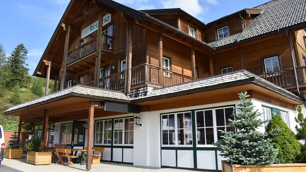 Un chalet en bois doté d’un balcon, de grandes fenêtres et d’une terrasse couverte.