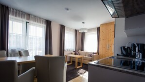 Un salon moderne comprenant un canapé, une table à manger et un coin cuisine avec un évier et une cuisinière.