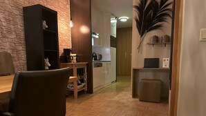 A modern kitchen with wooden cabinets, a dining area with a table and chairs, and a decorative wall piece. - Apartment # 14 with balcony (Turrach)