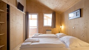 Une pièce en bois avec deux lits, une fenêtre et une lampe fixée au mur.
