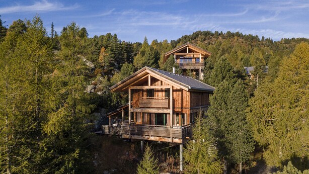 Une cabane en bois dotée d’un balcon au niveau inférieur et d’un étage supérieur séparé, également pourvu d’un balcon.