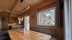 Une cuisine moderne avec des meubles en bois, une grande table à manger en bois et des luminaires suspendus.