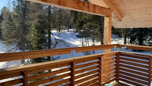 Une terrasse en bois offrant une vue sur une forêt enneigée.