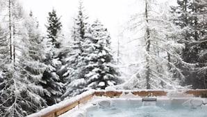Ein Whirlpool, umgeben von schneebedeckten Bäumen.