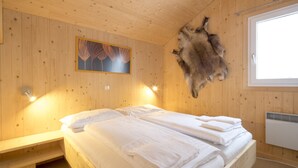 Et trægulvsrum med en seng, et opsat pelsværk og et maleri på væggen.