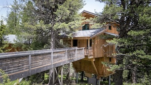 A treehouse with a wooden deck and a small entrance. - Chalet # 20 with IR-sauna and whirlpool bath (Turrach)