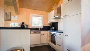 A compact kitchen with white cabinets, a microwave, a coffee maker, and a stove. - Chalet # 20 with IR-sauna and whirlpool bath (Turrach)