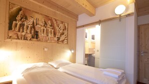 Ein Hotelzimmer mit einem großen Bett, einem Holz-Kopfteil, einem Wandbild und einem durchgegangenen Tür erkennbaren Badezimmer.