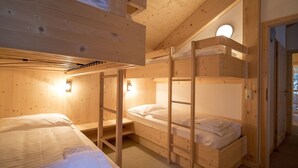 En stuga byggd av trä med våningssängar, ett sluttande tak och ett runt takfönster.