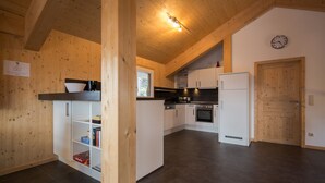 Una cucina moderna con mobili bianchi, un piano di lavoro nero e un soffitto in legno.