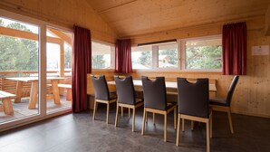 Un interno in legno con zona pranzo, un tavolo lungo e quattro sedie.