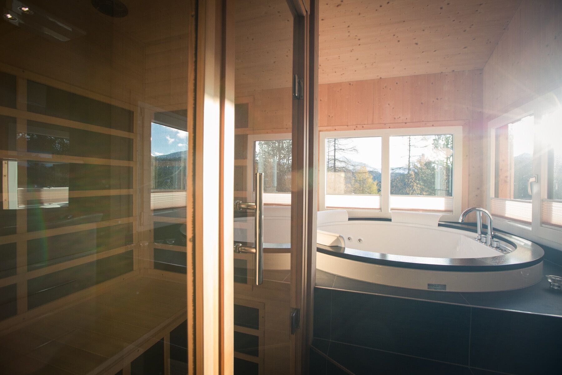 Een moderne badkamer met een vrijstaand bad, grote ramen en een douchecabine van glas.