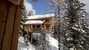 Une cabane en bois dotée d’un balcon, entourée d’arbres couverts de neige.