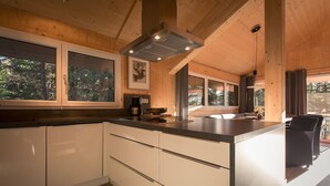 Een moderne keuken met houten balken, grote ramen en een centraal kookeiland.