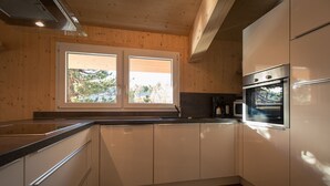 Une cuisine avec des armoires en bois, un évier à deux bacs et un four encastré.