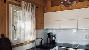 Una cocina moderna con paredes de madera, encimera negra, armarios blancos, y lavavajillas y horno Bosch.