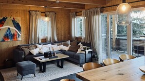 Una sala de estar acogedora con techo de madera, un sofá, una mesa de centro y una mesa de comedor con sillas.