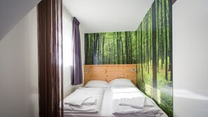 A bedroom with a bed, wooden headboard, and a forest mural on the wall. - Studio # 13 with Balcony (Turrach)