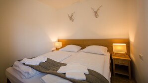 A neatly made bed with white linens, two wall-mounted deer antlers, and bedside lamps. - Apartment # 12 with balcony (Turrach)