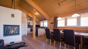 L’intérieur d’un chalet accueillant, avec une cheminée, une table à manger en bois et des chaises.