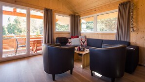 L’intérieur d’un chalet chaleureux, avec un plafond en bois, un ensemble de canapés et une table à manger.