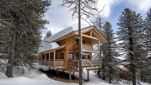 Une cabane en bois dotée d’un balcon, entourée d’arbres couverts de neige.