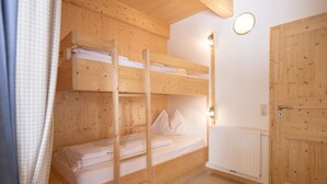 A bunk bed room with wooden walls, a white radiator, and a door. - Chalet #26 with IR-sauna and indoor whirlpool (Turrach)
