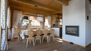 L’intérieur d’un chalet en bois chaleureux et accueillant, avec un coin repas, une cheminée et une cuisine.