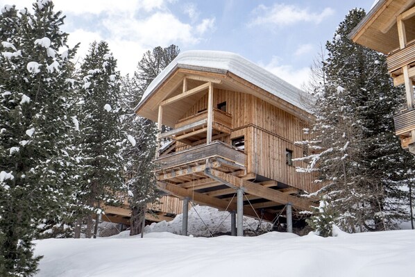 Een houten chalet met een balkon, omgeven door met sneeuw bedekte bomen.