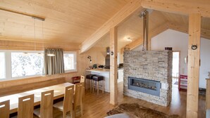 A wooden interior with a dining area, a stone fireplace, and a fur rug.