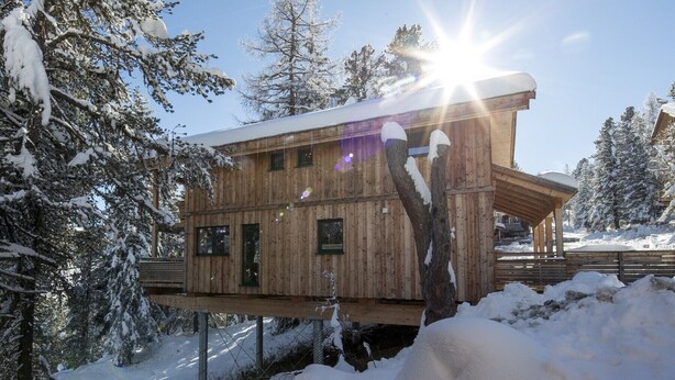 A wooden cabin with a balcony, surrounded by snow-covered trees. - Chalet #30 with IR-sauna and indoor whirlpool (Turrach)