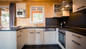 Een moderne keuken met witte kastjes, een zwart aanrecht en roestvrijstalen apparatuur, waaronder een oven en een vaatwasser.
