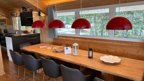 Una cucina moderna con un'isola in legno, sedie nere e lampade a sospensione rosse.