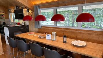 A modern kitchen with a wooden island, black chairs, and red pendant lights.