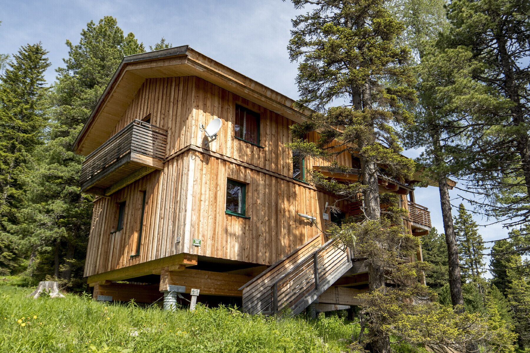 A wooden cabin with a balcony and a staircase leading to an upper level.