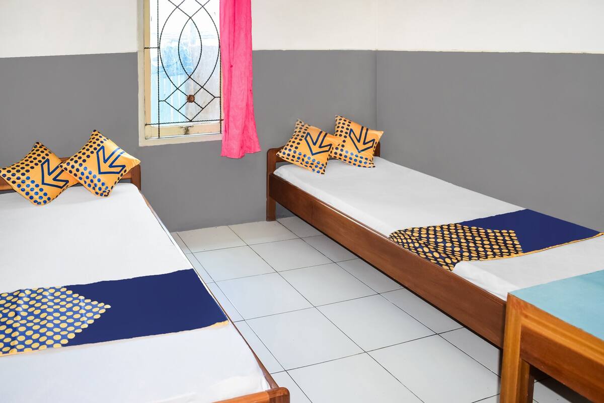 A room with two single beds, each with patterned pillows and a blue and white bedspread.