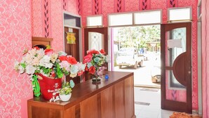A reception area with a wooden counter, floral arrangements, and a view of the street outside. - Hotel O Penginapan Widodo (Sebulu)