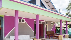 A colorful house with a porch, white furniture, and a satellite dish. - Hotel O Penginapan Widodo (Sebulu)