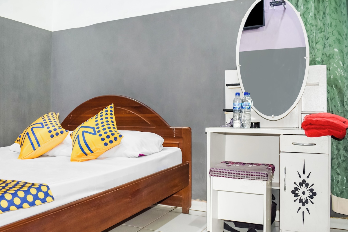 Ein Schlafzimmer mit einem hölzernen Bett, einem weißen Nachttisch mit Spiegel und einem grünen Vorhang.