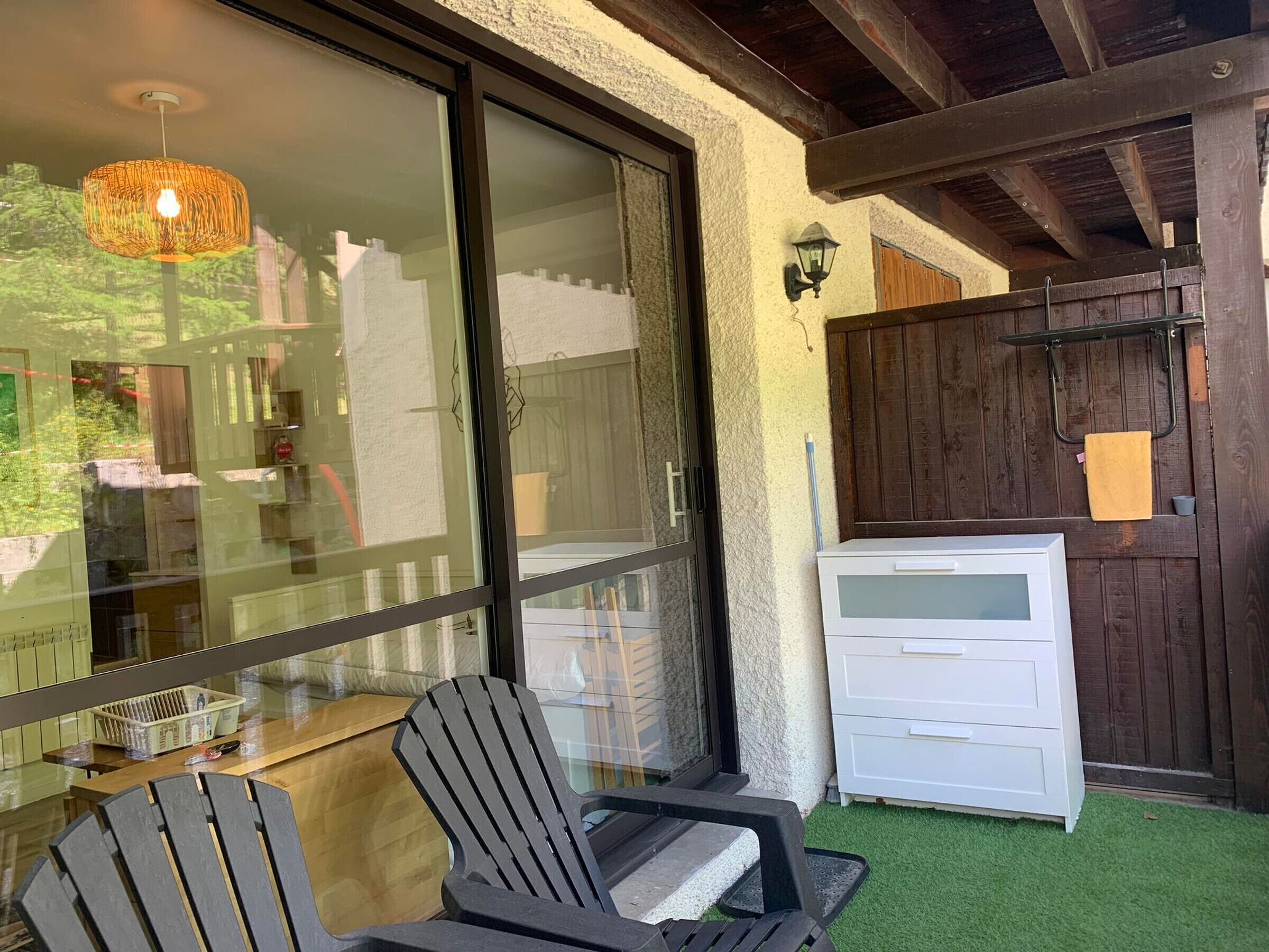 A patio area with a glass door, a white cabinet, and a black chair.