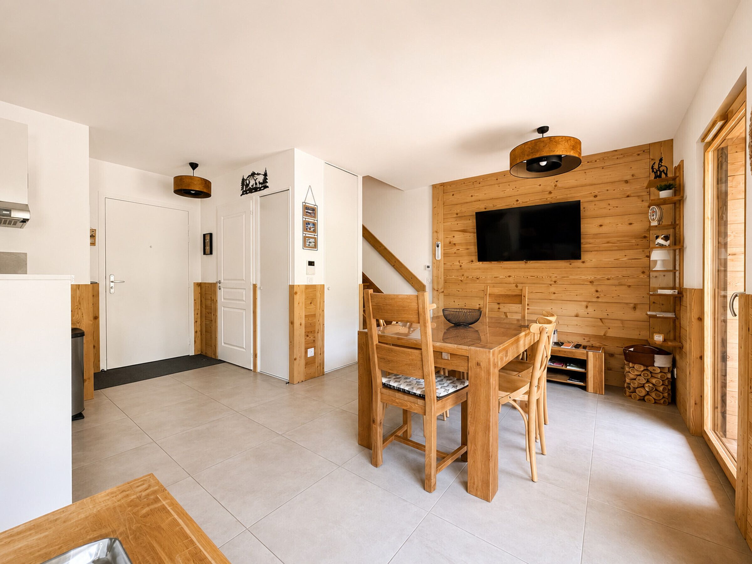 Un interior moderno con comedor, paredes de madera, televisor de pantalla plana y una escalera.