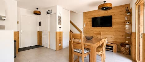 Ein modernes Interieur mit Essbereich, Holzwänden, einem Flachbildfernseher und einer Treppe.