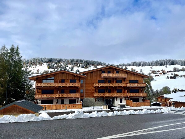 Eine Holzhütte mit zwei Balkonen, umgeben von schneebedeckten Hügeln.
